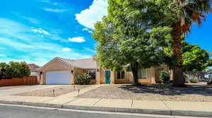 Obstructed view of property with stucco siding, a garage, concrete driveway, and a tiled roof