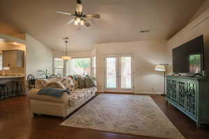 Living room with vaulted ceiling, a ceiling fan, french doors, and dark wood-style floors