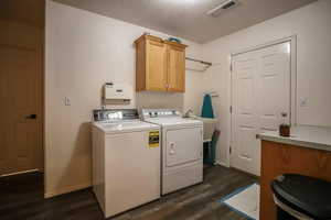 Laundry area with dark wood-type flooring, cabinet space, washer and dryer, and a textured ceiling