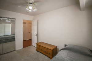 Bedroom with ceiling fan, light carpet, and a closet