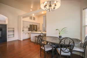 Dining space with a fireplace, built in features, dark wood-style flooring, and hanging lights