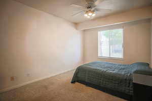 Carpeted bedroom featuring baseboards and a ceiling fan