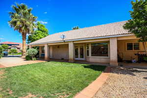 Back of property with stucco siding, a yard, french doors, and a tiled roof
