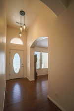 Foyer featuring arched walkways, dark wood-style flooring, and a high ceiling