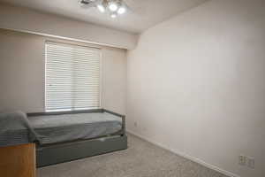 Carpeted bedroom with ceiling fan and baseboards