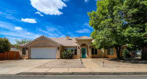 Mediterranean / spanish-style house featuring a tiled roof, an attached garage, stucco siding, driveway, and a chimney