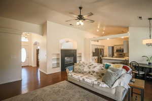 Living room with a fireplace, dark wood finished floors, vaulted ceiling, a ceiling fan, and recessed lighting