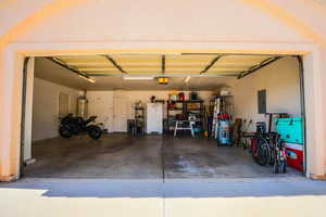Garage featuring freestanding refrigerator, electric panel, and gas water heater