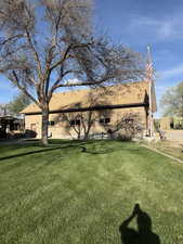 View of side of property featuring roof with shingles and a yard