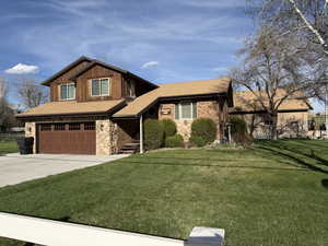 View of front of home featuring roof with shingles, a front yard, a garage, and driveway