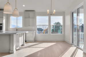 Unfurnished dining area with hanging lights, healthy amount of natural light, and light wood-style flooring