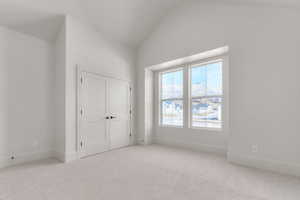 Unfurnished bedroom with carpet floors, vaulted ceiling, and a closet