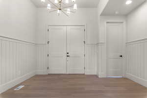 Foyer entrance featuring a chandelier, a wainscoted wall, and light wood finished floors