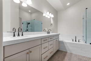 Bathroom featuring double vanity, a bath, a shower stall, and recessed lighting