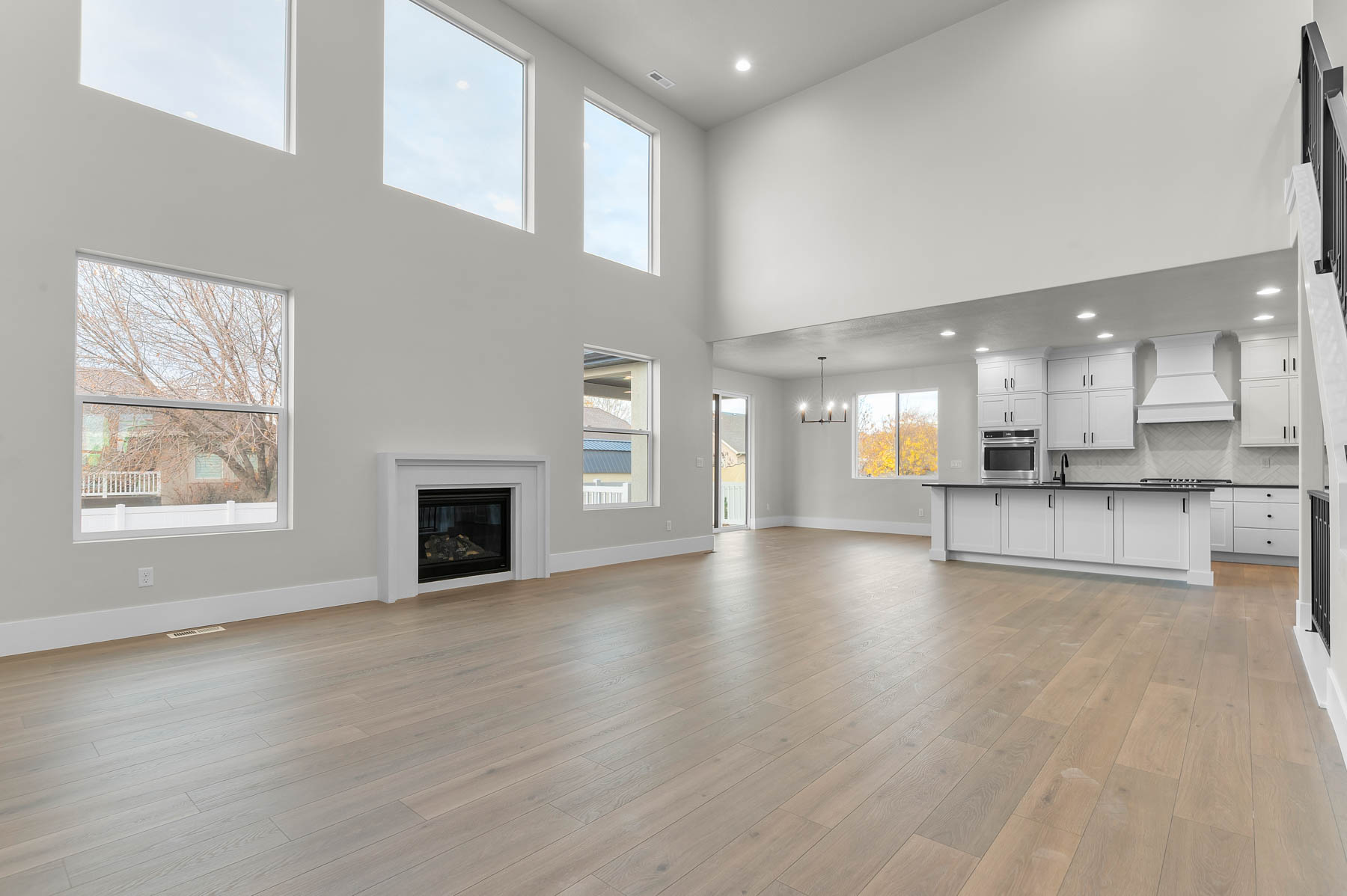 Unfurnished living room featuring hanging lights, a glass covered fireplace, a high ceiling, and light wood-style floors
