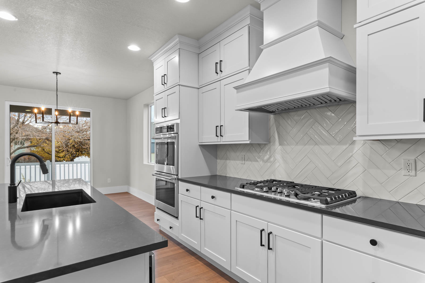 Kitchen featuring white cabinetry, hanging lights, a textured ceiling, light wood-style floors, and stainless steel appliances