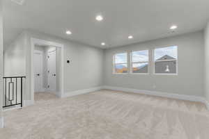 Empty room with light colored carpet and recessed lighting