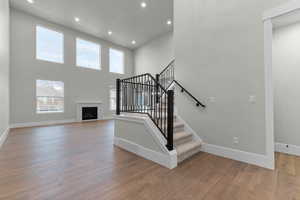 Stairs featuring a fireplace, a high ceiling, wood-type flooring, and recessed lighting