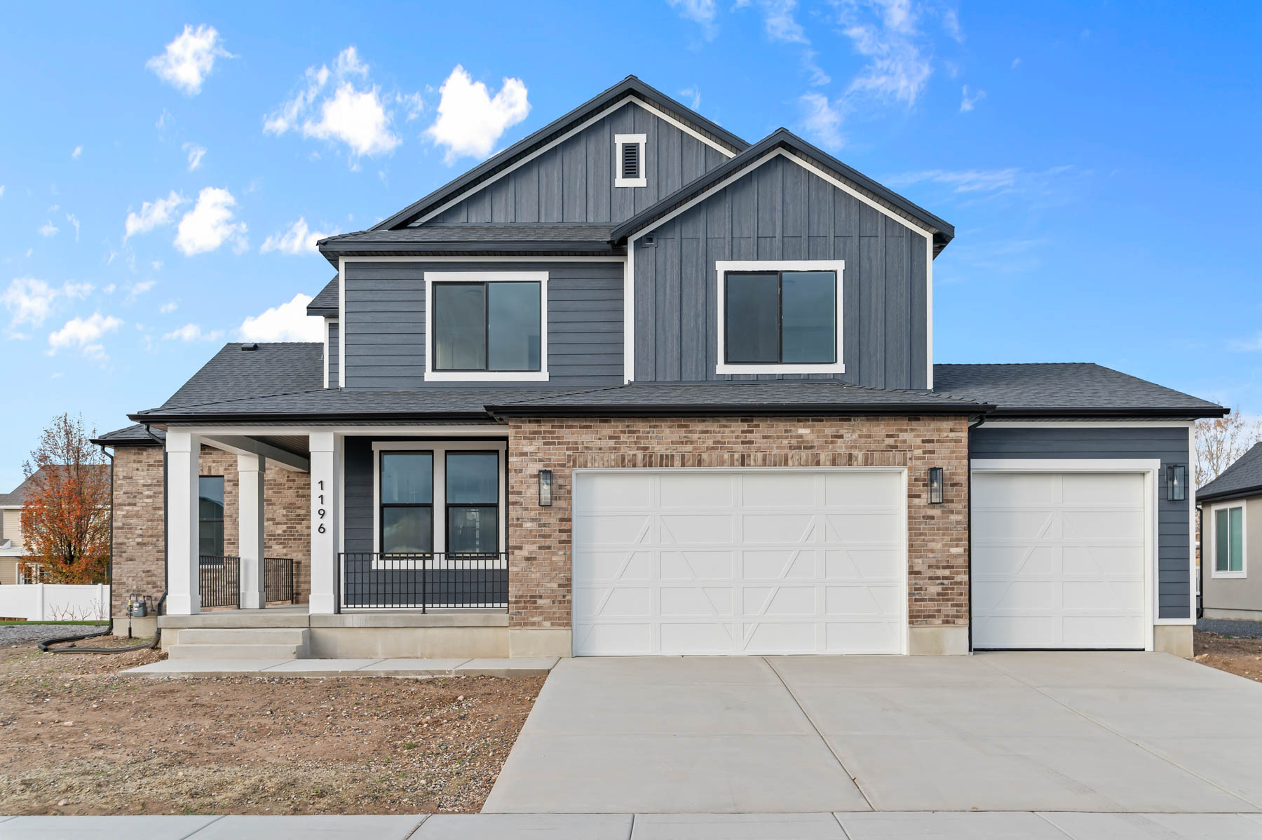 View of front of property featuring concrete driveway, covered porch, an attached garage, board and batten siding, and brick siding