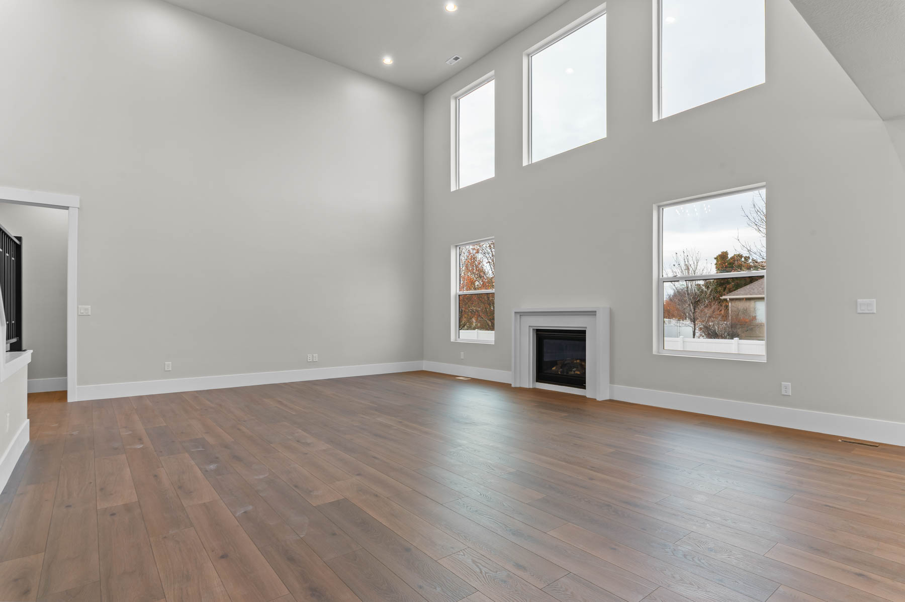 Unfurnished living room with a high ceiling, a fireplace, dark wood-style floors, and recessed lighting