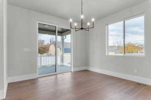 Unfurnished dining area featuring suspended lighting and dark wood finished floors