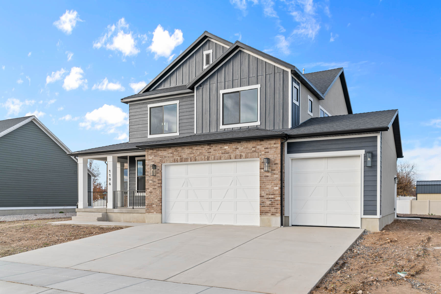 View of front of house with concrete driveway, covered porch, an attached garage, board and batten siding, and brick siding