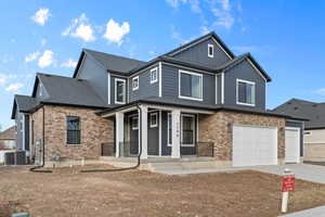View of front of property featuring a porch, brick siding, concrete driveway, board and batten siding, and a garage