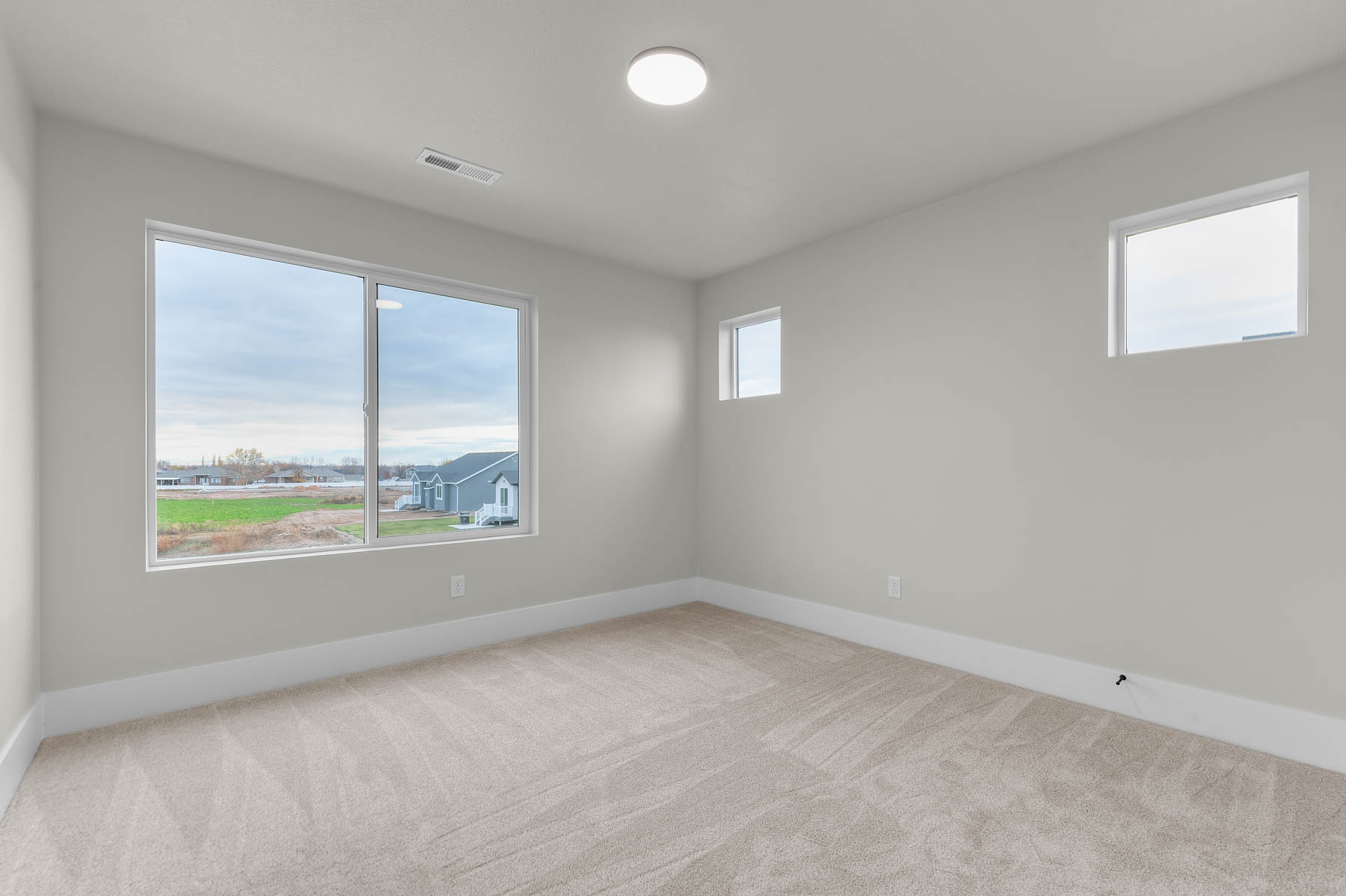 Empty room with light colored carpet and baseboards