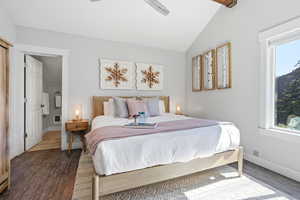 Bedroom with wood finished floors, ensuite bath, lofted ceiling, a ceiling fan, and heating unit