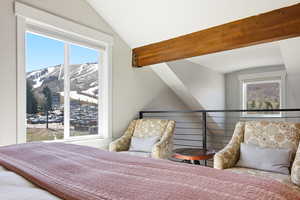 Bedroom with a mountain view, lofted ceiling, and multiple windows