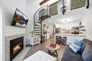 Living area with a tiled fireplace, light wood finished floors, and recessed lighting