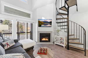 Living room with a high ceiling, a fireplace, wood finished floors, and plenty of natural light