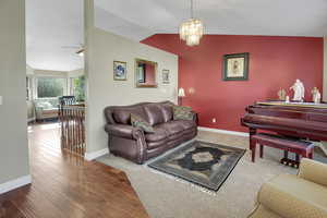 Living room with vaulted ceiling, light wood-style flooring, and hanging lights