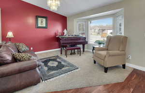Living area featuring vaulted ceiling, suspended lighting, and light wood-style floors