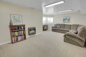 Carpeted living area with heating unit and baseboards