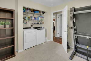Laundry area with light colored carpet, washing machine and clothes dryer, and heating unit