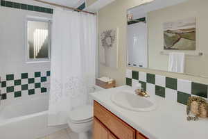 Bathroom featuring vanity, shower / bath combo, backsplash, and light tile patterned flooring