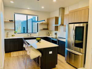 Kitchen with open shelves, stainless steel appliances, modern cabinets, a center island, and light wood-style floors