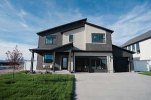 Modern home with driveway, brick siding, a garage, stucco siding, and a porch