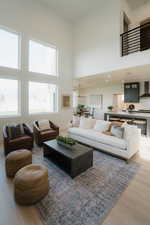 Living area featuring light wood-type flooring, a high ceiling, and hanging lights
