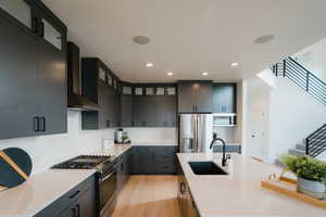 Kitchen featuring glass insert cabinets, stainless steel appliances, light wood finished floors, tasteful backsplash, and recessed lighting