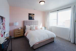 Bedroom with dark colored carpet and baseboards