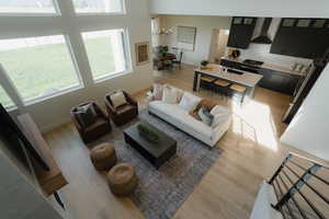 Living room with light wood finished floors, a high ceiling, and suspended lighting