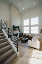 Living area with a high ceiling, light wood-type flooring, recessed lighting, and a large fireplace