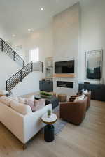 Living area with light wood finished floors, a high ceiling, a tile fireplace, and recessed lighting