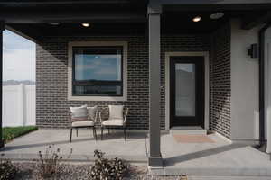 View of exterior entry with brick siding and a patio area