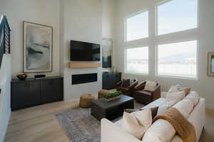 Living area featuring a high ceiling, light wood-style flooring, and a fireplace
