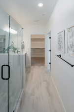 Bathroom with a walk in closet, vanity, and a shower stall
