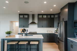 Kitchen featuring stainless steel appliances, a kitchen breakfast bar, a kitchen island with sink, recessed lighting, and backsplash