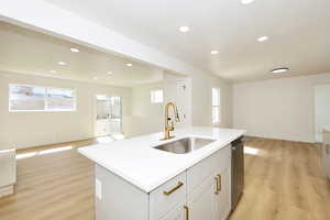 Kitchen with open floor plan, light wood-type flooring, a center island with sink, recessed lighting, and healthy amount of natural light